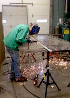 Ian Minor, of Moundsville and a senior student in welding at West Virginia Northern Community College, works on a section of a cage in a community service partnership with CHANGE, Inc., in Weirton.