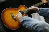 Dennehy playing his guitar with his feet.